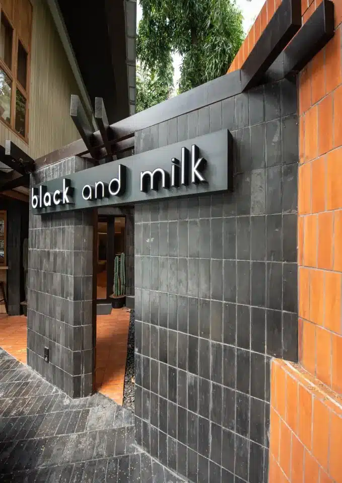 ป้ายชื่อ Black and Milk บนผนังกระเบื้องสีดำหน้าร้าน